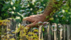 Beitragsbild: Hand am Zaun und grüne Blätter und Seifenblasen