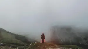 Mann auf einer Klippe mit Neben und Schatten und angedeuteten Flammen
